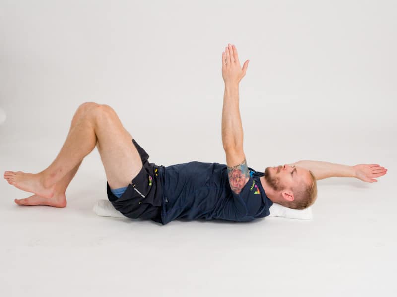 Bålkontroll i ryggliggande på handduk 4, slutpositition. Övning vid ryggskott, diskbråck, ischias och ont i rygg och bäcken.