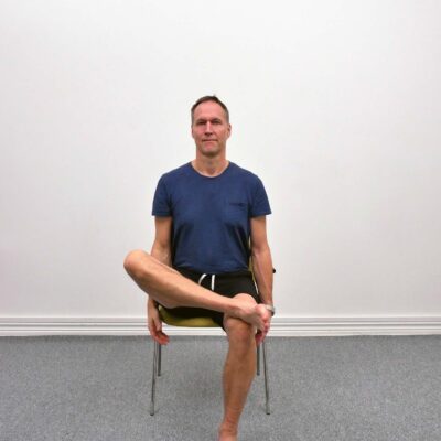 Sitting Ankle Knee Crossover startposition sittande på stol med båda fötterna i golvet och upprätt hållning