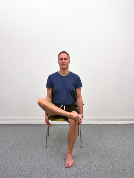 Sitting Ankle Knee Crossover startposition sittande på stol med båda fötterna i golvet och upprätt hållning