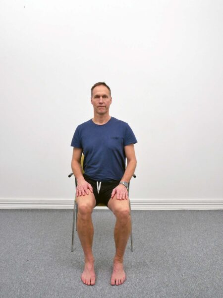 Sitting Chair Pelvic Twist med bäckenrotation där ena höften förs bakåt