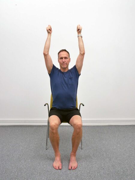 Sitting Overhead Extension med armar lyfta över huvudet och lätt bakåt