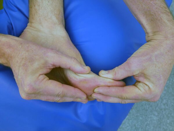 Person sitter och mobiliserar stortån med lätt drag och uppåt- och nedåtriktad rörelse.