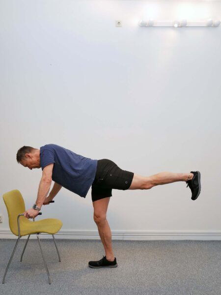 Kroppen är framåtlutad med ena benet lyft bakåt i linje med överkroppen.