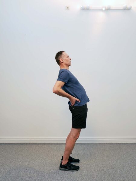 Mellanposition: Personen lutar överkroppen bakåt med lätt bakåtböjning i ländryggen.