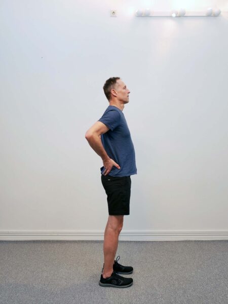 Startposition: Person står upprätt med händerna placerade mot nedre delen av ryggen.