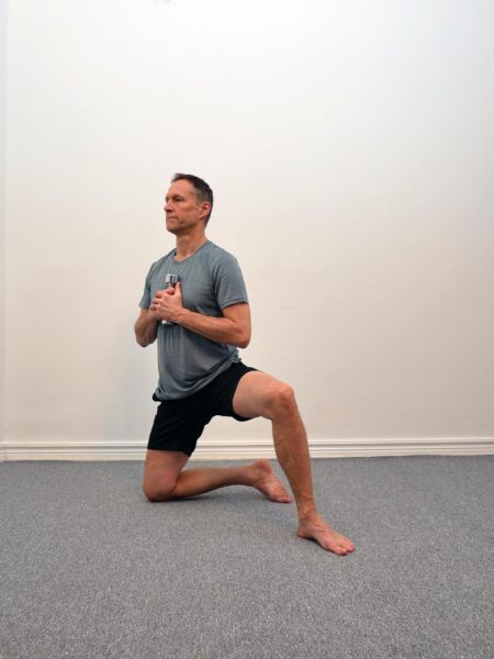 Person står i halvknästående med ena benet fram och överkroppen upprätt.