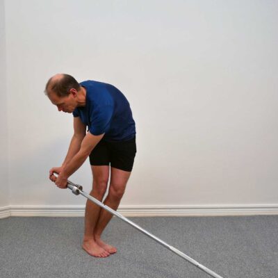 Person har fört skivstången ned mot knähöjd i roterad position.