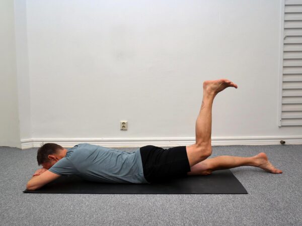 Låret är lyft 5–10 cm från golvet med stabil bål och aktiverad sätesmuskulatur.