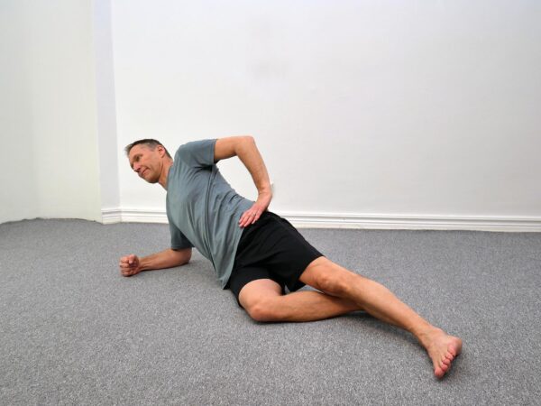 Startposition: Person ligger på sidan med knä i golvet och underarm placerad under axeln.