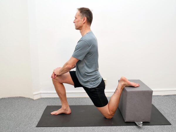 Bäckenet tippas bakåt och överkroppen hålls upprätt i stretchposition.