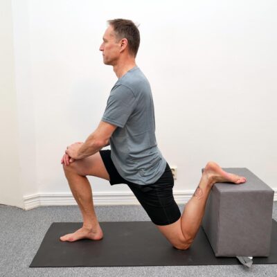 Person i knästående med ena foten placerad på stol bakom kroppen.