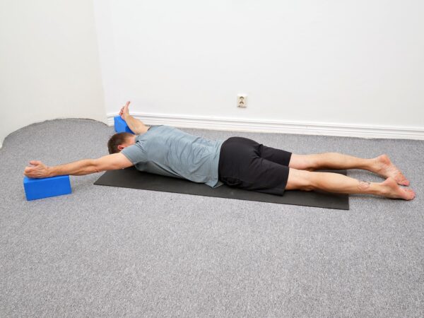 Person ligger på mage med armarna placerade på kuddar mer snett ut åt sidan och pannan mot underlaget.