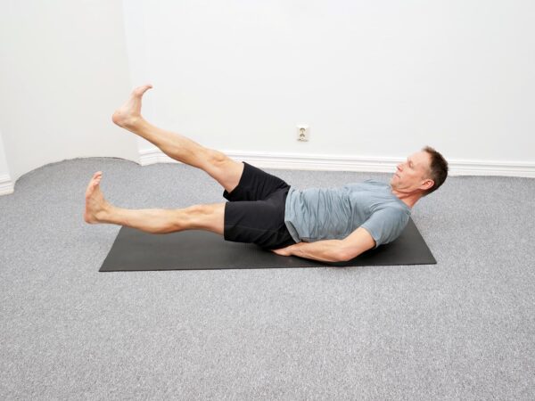 Person ligger på rygg med benen utsträckta och överkroppen lätt lyft.