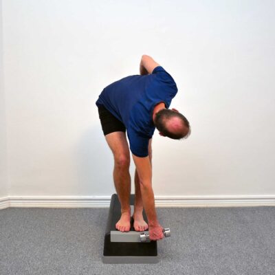 Person är maximalt framåtfälld med lätt rotation och hanteln nära golvet innan kontrollerad uppresning sker.