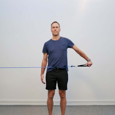 Stående med arm abducerad 90 grader och tumme pekad ned - empty can position med gummibandsmotstånd