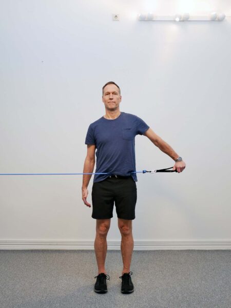 Stående med arm abducerad 90 grader och tumme pekad ned - empty can position med gummibandsmotstånd