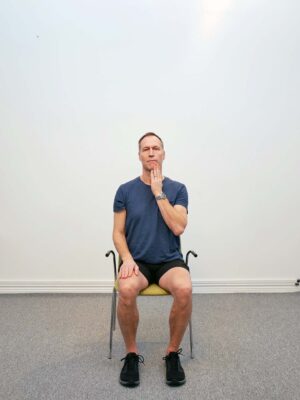 Sittande på stol med huvudet vridet åt sidan inför hand-assist med övertryck i nack-rotation